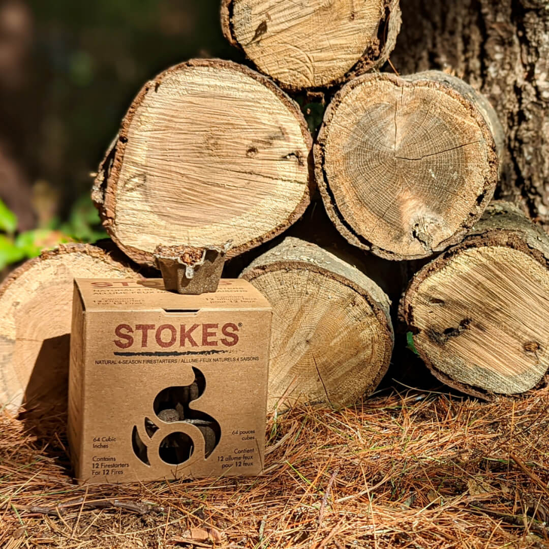 STOKES box in front of a stack of split firewood