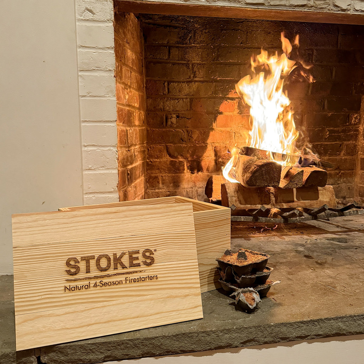 STOKES Fireside Box, pine box with the STOKES logo burned into the lid, beside a lit fireplace